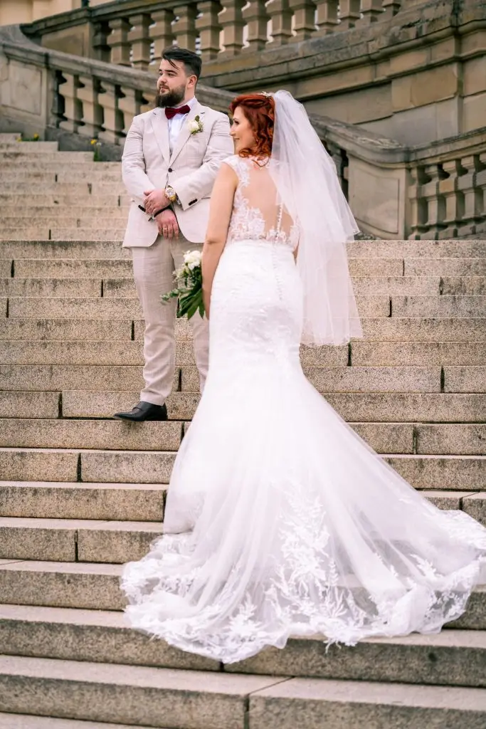 Ein klassisches Hochzeitsfoto. Es sind die Braut und der Bräutigam zu sehen. Sie stehen auf der Treppe von Schloss Solitude.